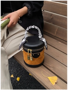 Detail of a cylinder bucket bag with quilted suede and a heart-pattern scarf handle
