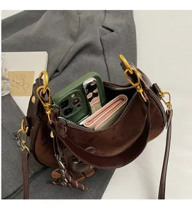 Détail macro du sac croissant en daim marron montrant l'espace intérieur pour mobile