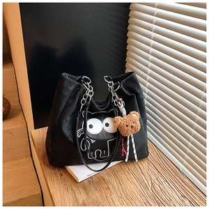 Détail du sac cabas chat noir avec chaîne et porte-clés ours sur un bureau en bois