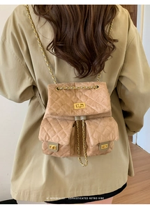 Detail of khaki quilted faux suede backpack featuring gold metal twist locks and chain strap