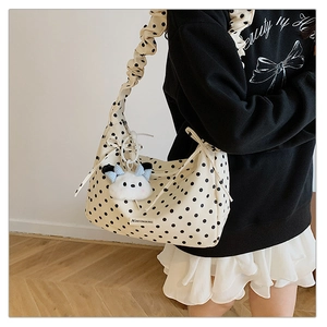 Close-up of cream polka dot shoulder bag with ruffled strap and plush dog charm