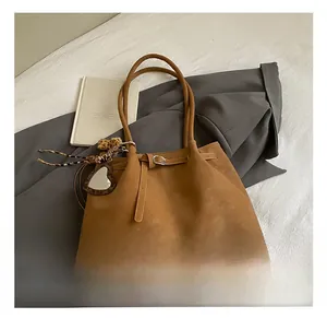 Nahaufnahme der braunen Wildledertasche mit Herzanhänger und Leopardenband auf grauem Anzug