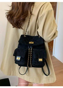 Detail of retro quilted suede backpack with gold chain straps on khaki trench coat