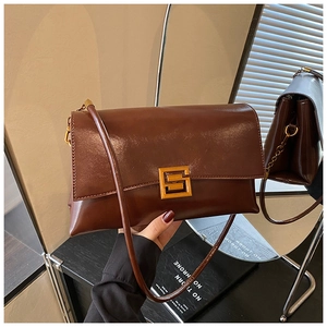 Detail of vintage brown leather handbag featuring a prominent gold square buckle closure