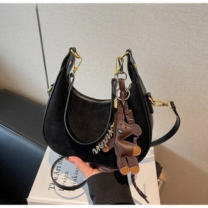 Détail du sac hobo noir en cuir avec broderie fashion et breloque ours marron