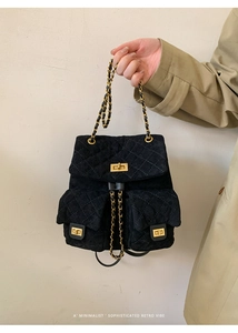 Detail of black quilted suede backpack featuring golden chain straps and twist locks