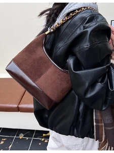 Vintage brown suede and leather hobo bag with metal chain strap worn by a model