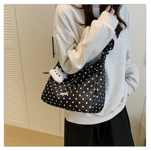 Close-up of black polka dot shoulder bag with a cute white plush bunny charm attachment
