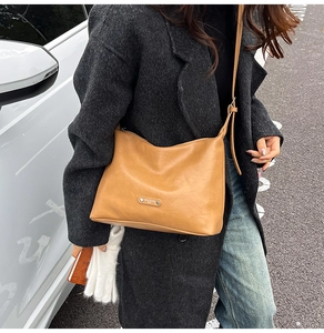 Detailed view of the brown retro leather shoulder bag with metallic brand plate and adjustable strap