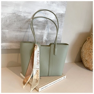 Detailansicht der salbeigrünen Tote Bag mit Seidenschal auf Vintage-Büchern platziert