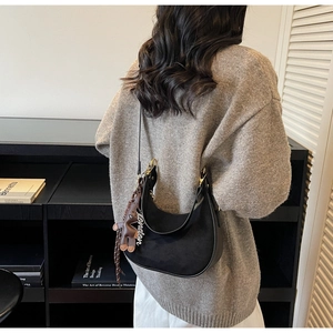 Détail du sac hobo noir avec boucles dorées et un charmant ours en peluche