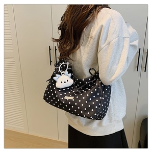 Polka dot shoulder bag with cute plush pendant shown on model in a home setting