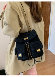 Close-up of black quilted backpack with gold clasp and chain straps on female model