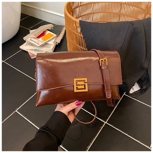 Close-up of retro dark brown leather bag with glossy finish and gold geometric buckle