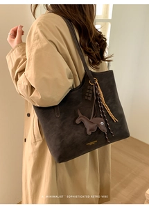 Close-up of dark brown tote bag with decorative charms and minimalist leather texture