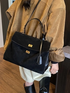 Minimalist large capacity black matte tote bag with gold hardware shown on a model side view