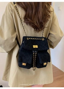 Detail of vintage black quilted backpack with golden chain straps and turn-lock closures