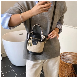 Detail of a color-block cylinder bucket bag with heart-print scarf and gold hardware