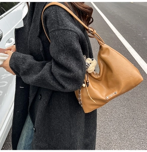 Close-up of brown faux leather hobo bag with metal brand plate and cute bear charm
