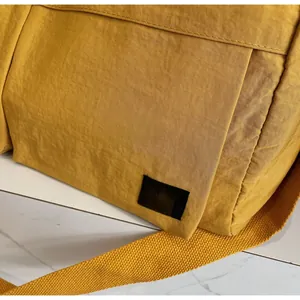 Close-up of bright yellow waterproof nylon fabric and woven brand label on the duffel bag