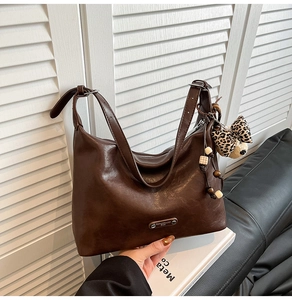 Detail of dark brown leather tote bag featuring leopard print bow and vintage wooden beads