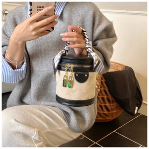 Detail of a beige suede bucket bag with black leather trim and heart pattern silk scarf handle
