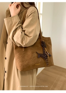 Close-up of caramel brown tote bag with dachshund charm and gold lettering detail