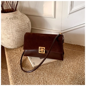 Close-up of retro brown shoulder bag with suede patchwork and gold square buckle