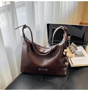 Close-up of retro dark brown shoulder bag with silver zipper and plush bear pendant