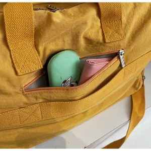 Macro view of bright yellow travel bag showing front zipper pocket and interior storage space