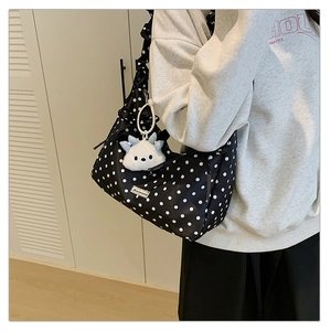Detail view of black polka dot shoulder bag with a cute white plush bear charm