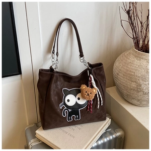 Détail du sac cabas en daim marron avec broderie de chat noir et charm ours en peluche