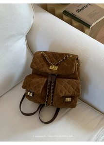 Detailed close-up of brown quilted suede backpack with gold chain and turn-lock closure