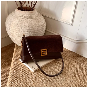 Detail of dark brown leather handbag with gold metal clasp on decorative background
