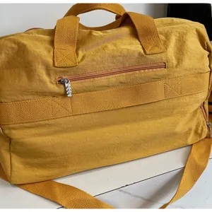 Detail of soft yellow nylon travel bag with front zipper pocket on marble surface