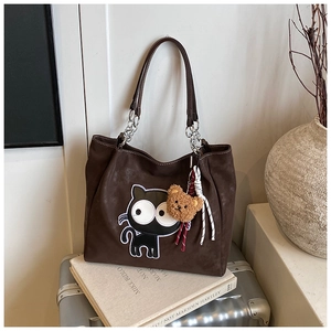 Détail d'un sac cabas chat marron foncé avec chaînes argentées et charme d'ours peluche