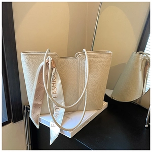 Detailaufnahme der cremefarbenen Ledertasche mit modischem Seidenschal und langem Schultergurt