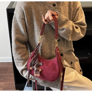 Détail du sac hobo en daim bordeaux avec breloque Love dorée et pendentif ours