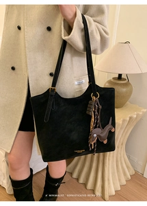 Detail of black suede tote bag with golden lettering and cute dachshund charm