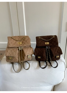 Detail of dark brown and khaki suede quilted backpacks with chain straps and turn-locks