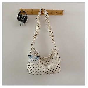 Detail of beige polka dot shoulder bag with scrunchie strap and plush puppy charm