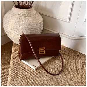 Detail of vintage brown leather handbag with luxury gold buckle on a minimalist background