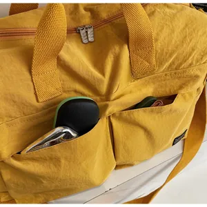 Detailed macro view of large yellow travel bag with functional front pockets and nylon texture