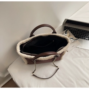 Detail view of brown suede tote bag with faux shearling trim and gold chain strap