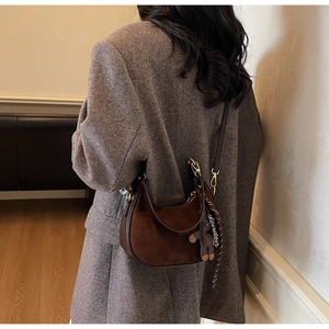 Détail du sac demi-lune en daim marron foncé avec foulard et breloque ours mignon