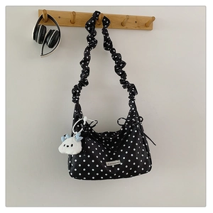 Close-up of black polka dot bag with ruffled strap and cute white cloud pendant detail