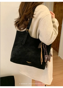 Detail of black suede tote bag with golden lettering and cute decorative horse charm
