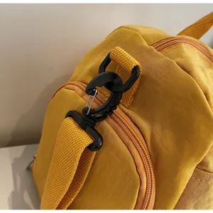 Detail of durable black hook and sturdy nylon strap on a bright yellow travel bag