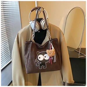 Détail du sac cabas en daim marron foncé avec imprimé chat et pendentif ours