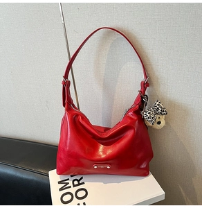 Detail of red leather shoulder bag featuring a silver metal logo and leopard print bear charm